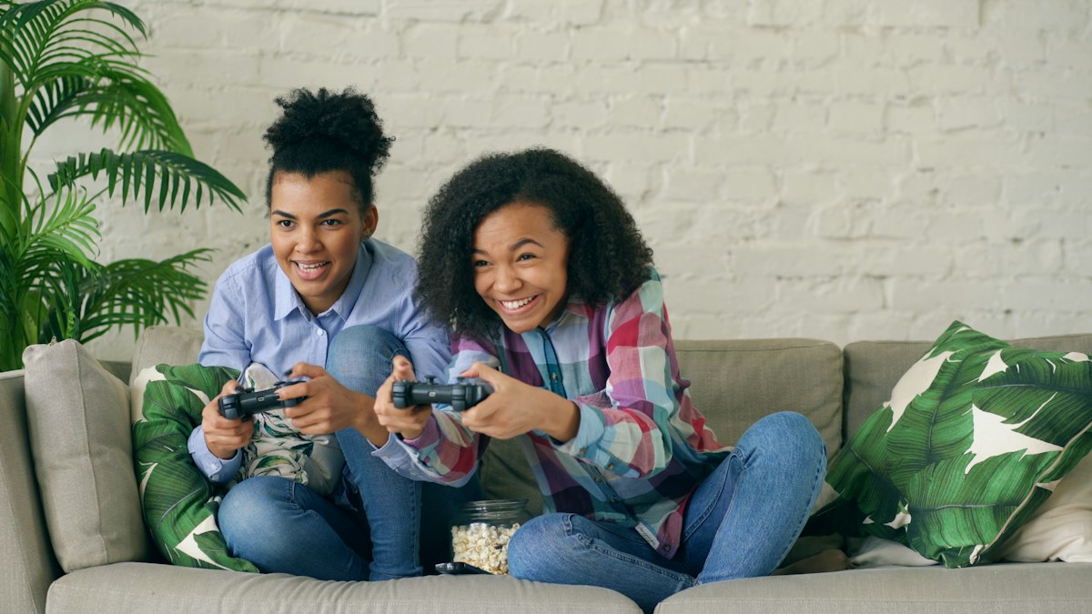 Two friends laughing while playing a console game