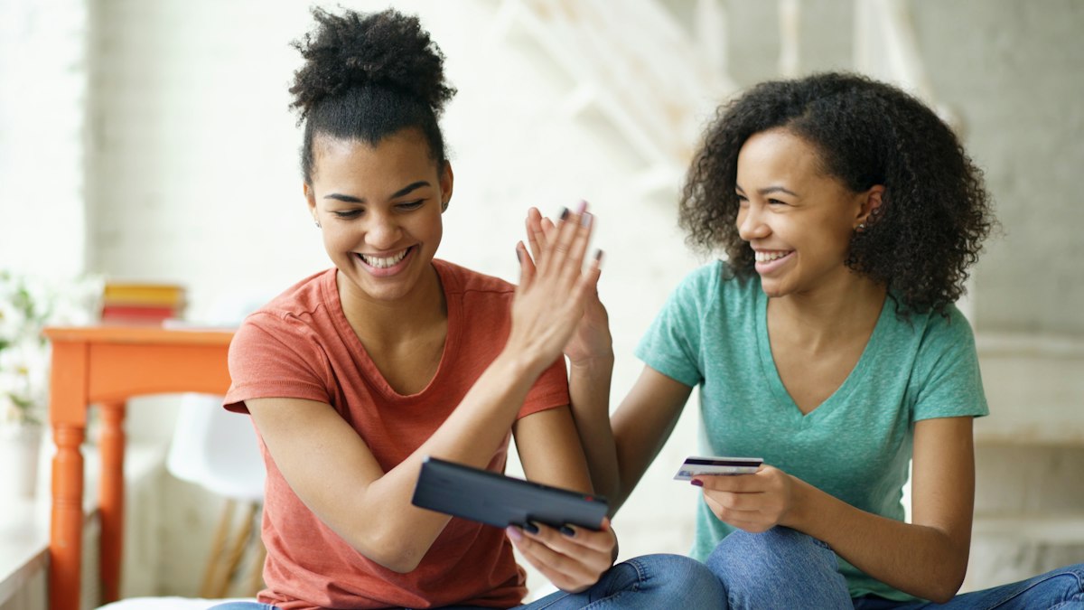 Two friends high-fiving over a tablet